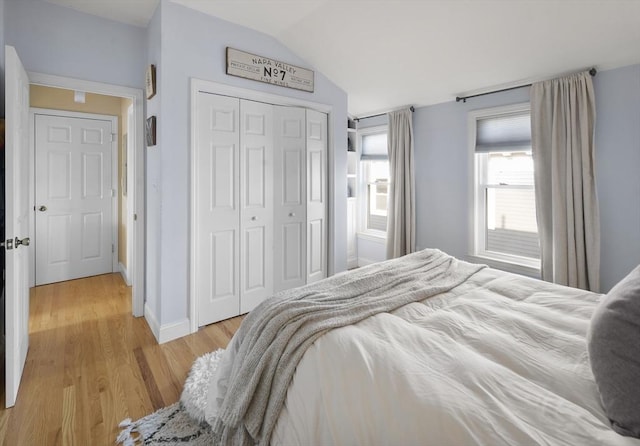 bedroom with lofted ceiling, light wood-type flooring, and a closet