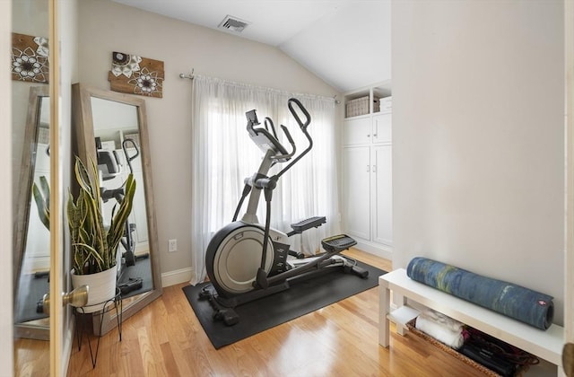 workout area with vaulted ceiling and light hardwood / wood-style flooring