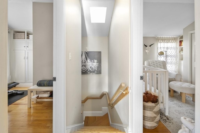 hallway with a skylight and hardwood / wood-style flooring