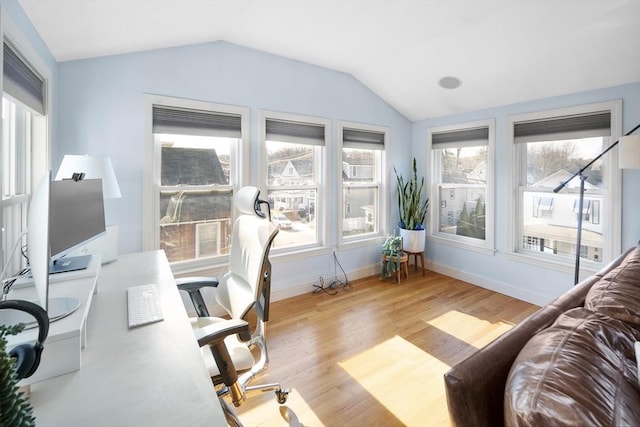 home office featuring lofted ceiling, light hardwood / wood-style floors, and a healthy amount of sunlight