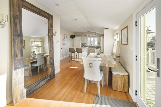 dining space with vaulted ceiling and light wood-type flooring