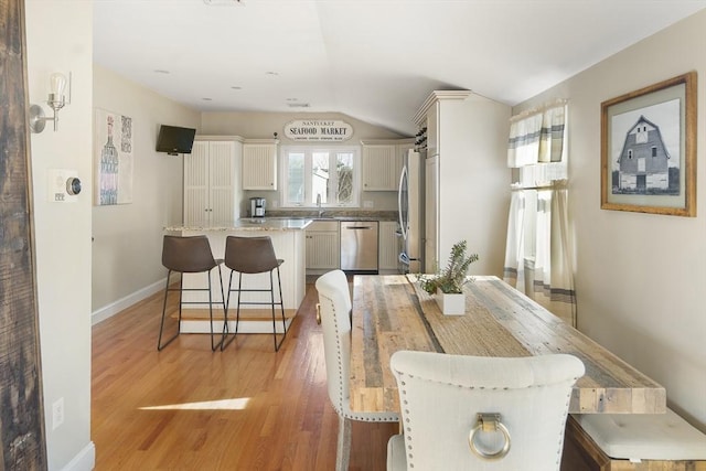 dining area featuring light wood-type flooring, lofted ceiling, and sink