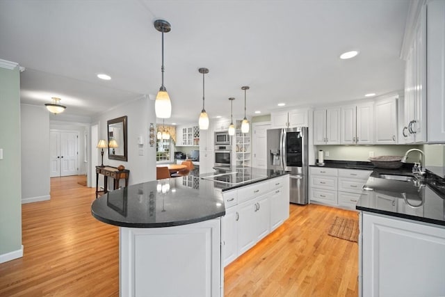 kitchen with light wood finished floors, white cabinets, appliances with stainless steel finishes, a center island, and a sink