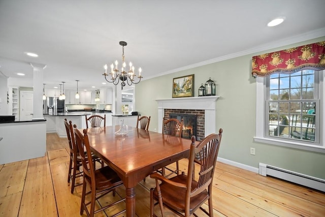 dining area featuring a fireplace, a baseboard radiator, light wood-style floors, ornamental molding, and baseboards