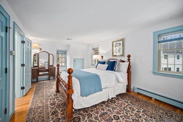 bedroom with visible vents, baseboard heating, and light wood-style flooring