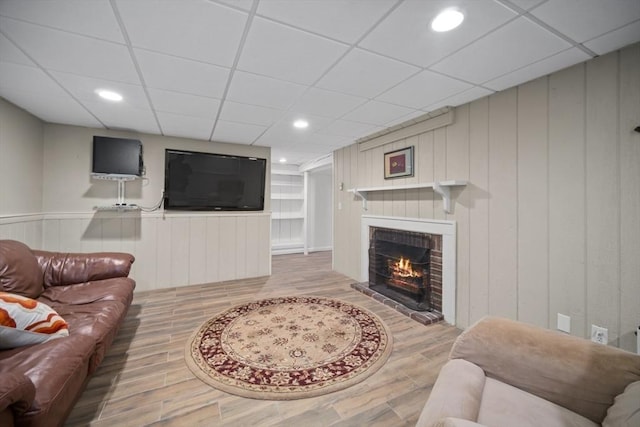 living area featuring a drop ceiling, a fireplace, wood finished floors, and recessed lighting