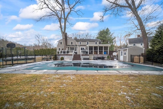 rear view of property featuring an outbuilding, fence, a sunroom, and a fenced in pool