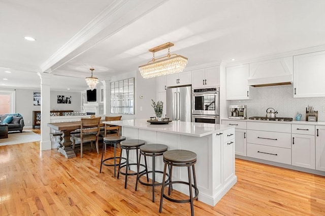 37-1/2 Federal St, Newburyport, MA 01950 - kitchen with premium range hood, stainless steel appliances, ornate columns, light wood finished floors, and recessed lighting