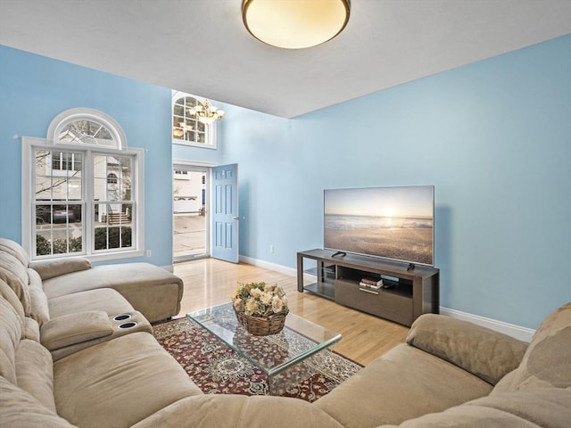 living area featuring baseboards, a chandelier, and wood finished floors