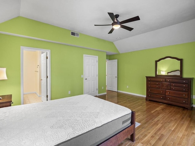 bedroom featuring baseboards, visible vents, a ceiling fan, wood finished floors, and vaulted ceiling