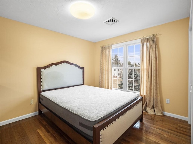 bedroom featuring visible vents, baseboards, and wood finished floors