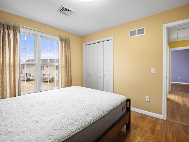 bedroom with baseboards, a closet, visible vents, and wood finished floors