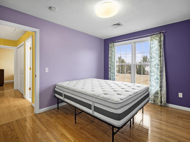 bedroom featuring attic access, baseboards, visible vents, and hardwood / wood-style floors