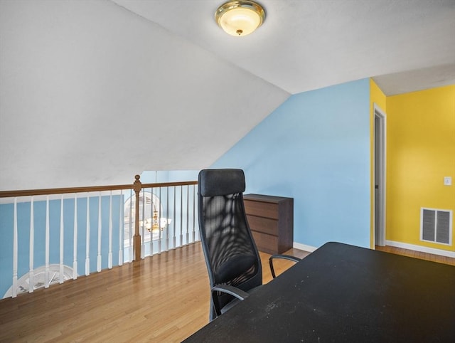 home office with baseboards, visible vents, vaulted ceiling, and wood finished floors