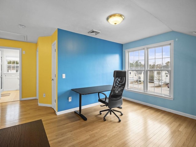 office with baseboards, wood-type flooring, visible vents, and a healthy amount of sunlight