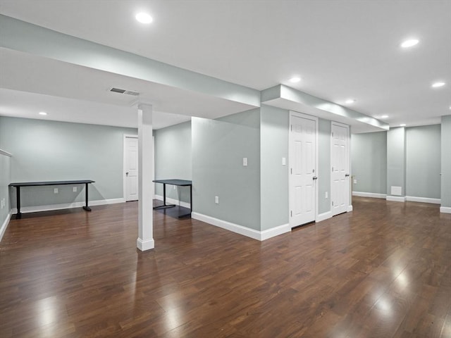 finished below grade area featuring baseboards, dark wood-style flooring, visible vents, and recessed lighting