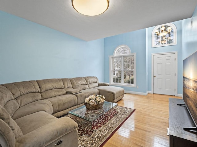 living room with an inviting chandelier, light wood-style flooring, and baseboards