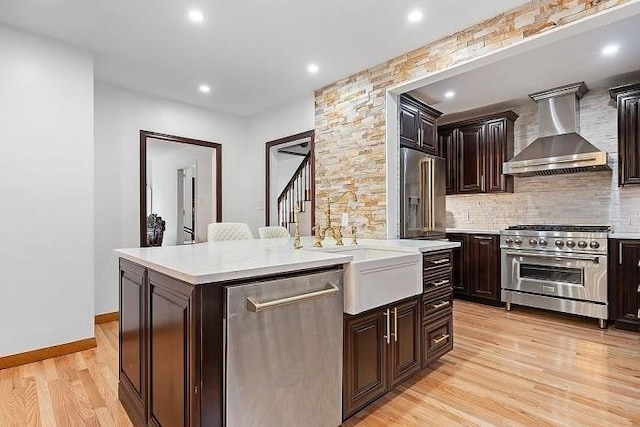 21 Parker St, Boston, MA 02129 - kitchen with wall chimney range hood, high end appliances, light countertops, light wood-style flooring, and a center island with sink