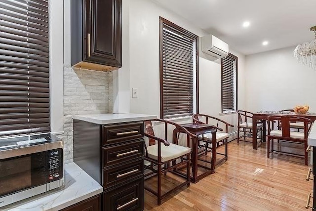 21 Parker St, Boston, MA 02129 - kitchen with stainless steel microwave, a wall mounted air conditioner, light wood-style floors, a chandelier, and dark brown cabinets