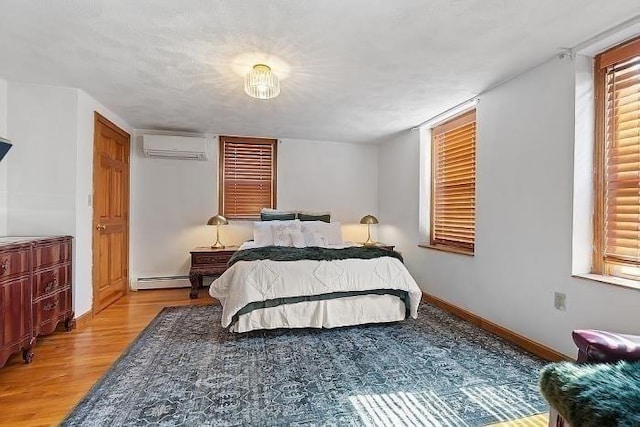 21 Parker St, Boston, MA 02129 - bedroom with an AC wall unit, wood finished floors, baseboards, and baseboard heating