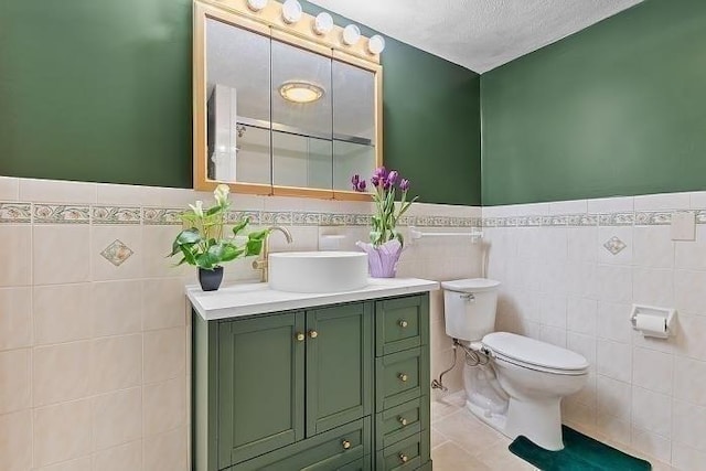 21 Parker St, Boston, MA 02129 - bathroom featuring toilet, tile walls, vanity, a wainscoted wall, and tile patterned flooring