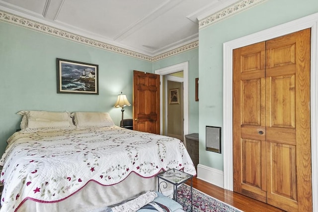 bedroom featuring wood finished floors, crown molding, and baseboards