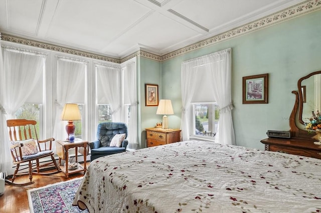 bedroom featuring baseboard heating, wood finished floors, and crown molding