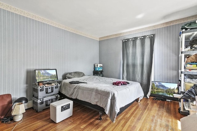 bedroom with wood finished floors and wallpapered walls