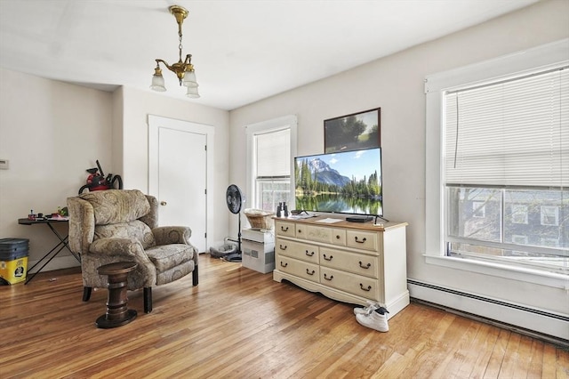 living area with an inviting chandelier, a baseboard radiator, and light wood-style floors