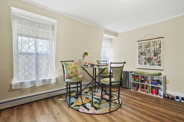dining space with wood finished floors, ornamental molding, and a baseboard heating unit