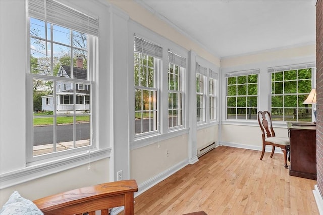 sunroom featuring baseboard heating, crown molding, baseboards, and wood finished floors