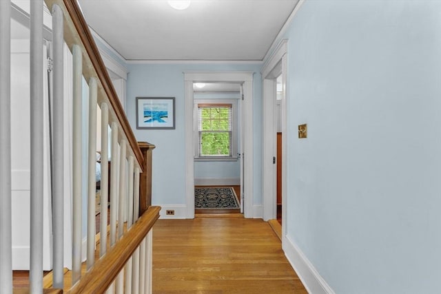 hall with stairs, light wood-type flooring, baseboards, and ornamental molding