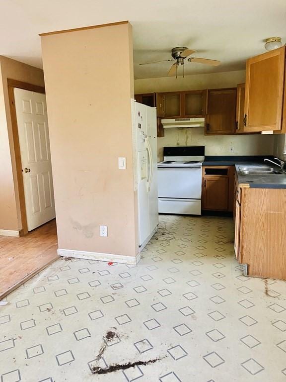 kitchen featuring dark countertops, a ceiling fan, a sink, white appliances, and under cabinet range hood