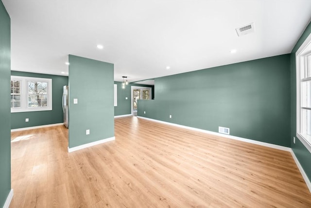 empty room with baseboards, visible vents, and light wood-type flooring