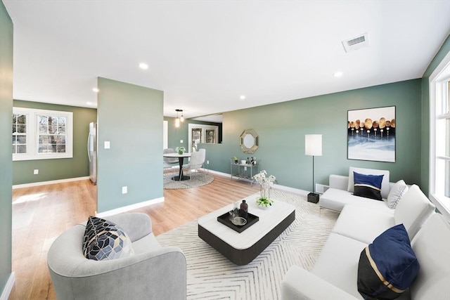 living area featuring visible vents, recessed lighting, baseboards, and wood finished floors