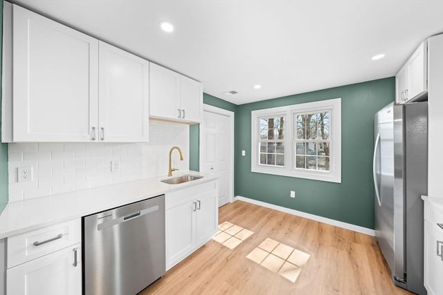 kitchen with backsplash, white cabinetry, stainless steel appliances, and a sink