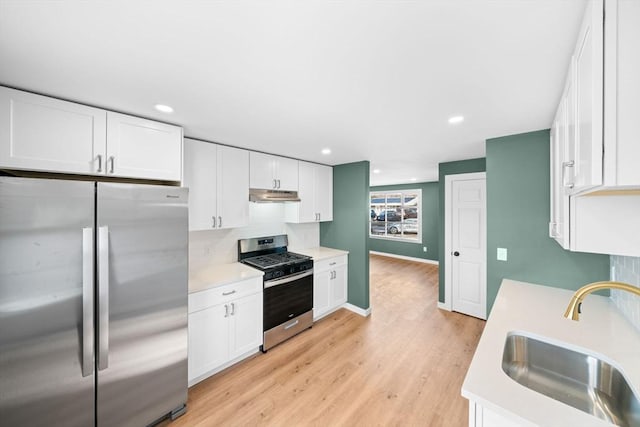 kitchen featuring under cabinet range hood, stainless steel appliances, light countertops, and a sink