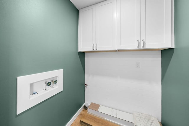 laundry room featuring cabinet space, hookup for a washing machine, baseboards, and wood finished floors