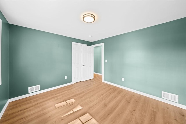 unfurnished room with wood finished floors, baseboards, and visible vents