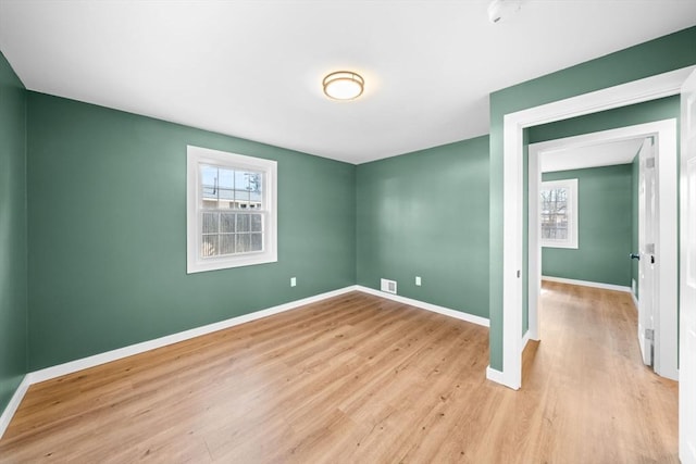 spare room with a wealth of natural light, visible vents, baseboards, and light wood-style floors