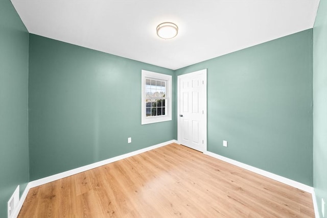 empty room featuring visible vents, baseboards, and wood finished floors