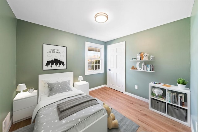 bedroom with visible vents, baseboards, and wood finished floors