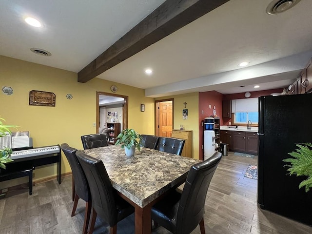 dining room with beam ceiling, hardwood / wood-style floors, and sink