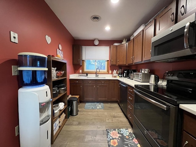 kitchen with stainless steel appliances, light hardwood / wood-style floors, and sink