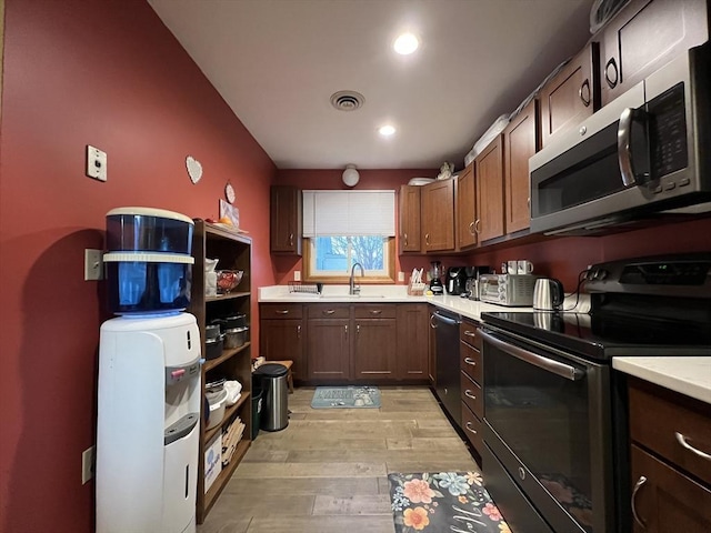 kitchen with sink, stainless steel appliances, and light hardwood / wood-style floors