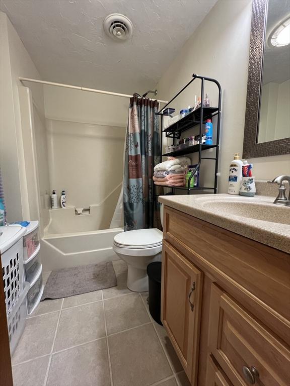 full bathroom with tile patterned flooring, vanity, toilet, and shower / bathtub combination with curtain