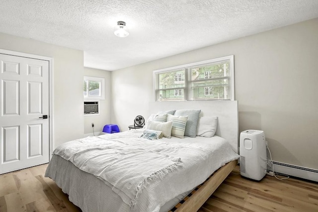 62 Progressive St, Worcester, MA 01604 - bedroom featuring light wood-type flooring, a baseboard heating unit, a textured ceiling, and cooling unit