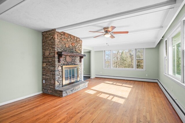 unfurnished living room with ceiling fan, beamed ceiling, a baseboard heating unit, a fireplace, and light wood-type flooring