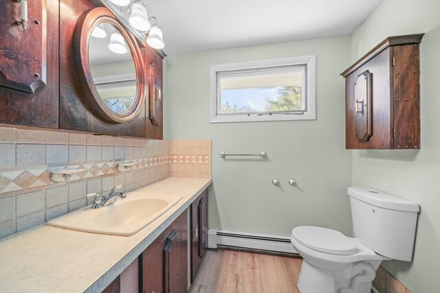 bathroom with a baseboard radiator, toilet, decorative backsplash, vanity, and hardwood / wood-style flooring