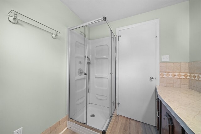 bathroom featuring hardwood / wood-style floors, vanity, and a shower with door